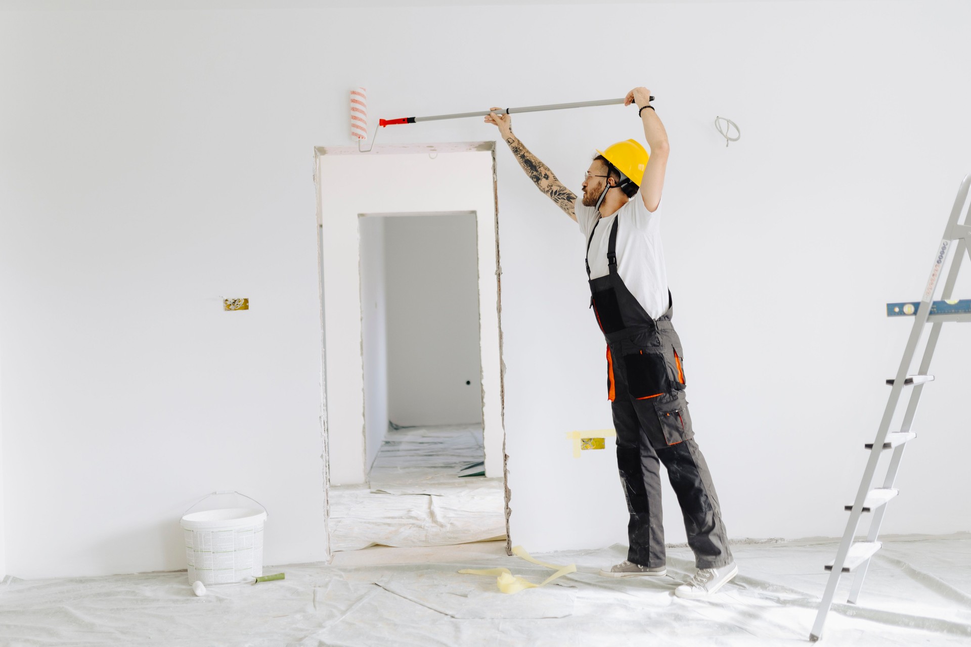 Young painter - construction worker painting a wall indoors